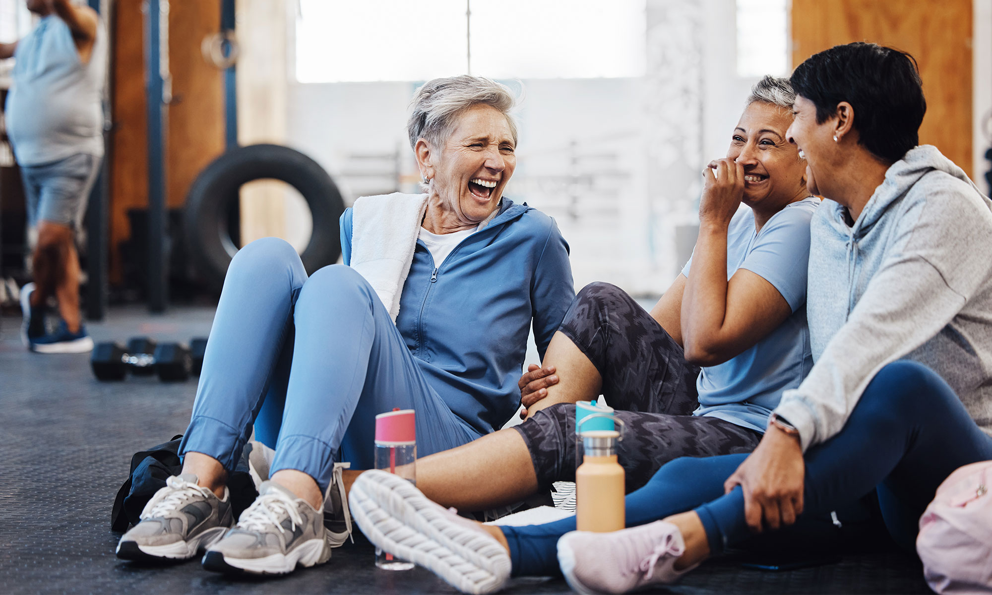 Three female friends laughing in the gym after a workout.